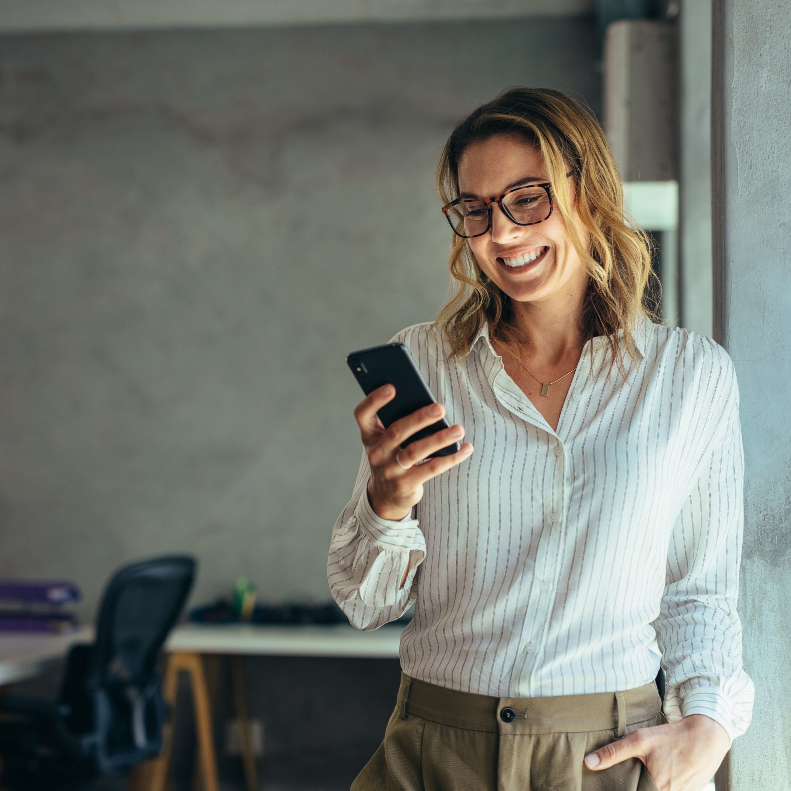 Smiling Businesswoman Using Phone In Office